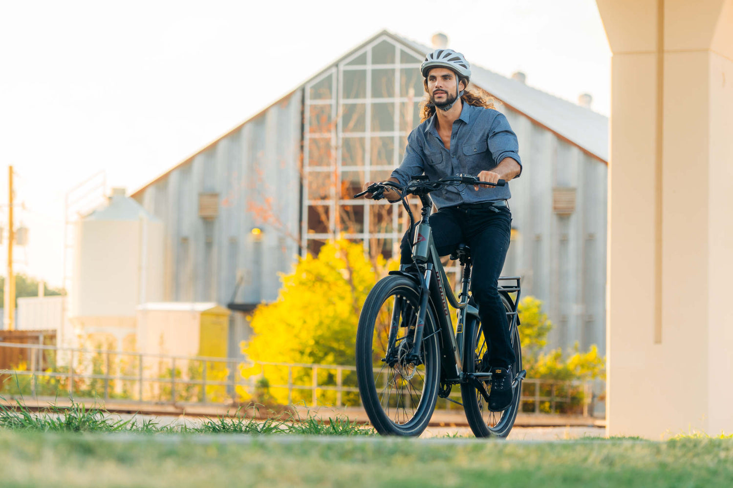 Commuter biking his electric Denago Commute 1 Top Tube bike down bike path in front of a business.