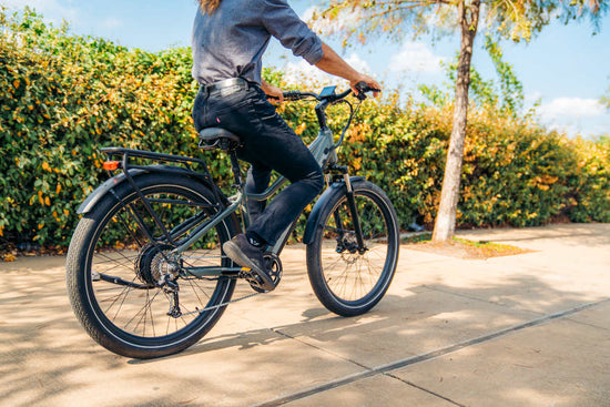 eBike rider, on a Denago Commute 1 Top Tube eBike, riding away on urban trail with hedges and trees lining the roads.