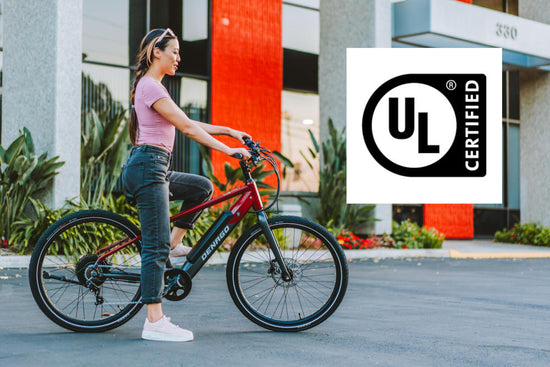 Woman on a top tube ebike looking ahead at an office building with the UL Certified logo overlaid.