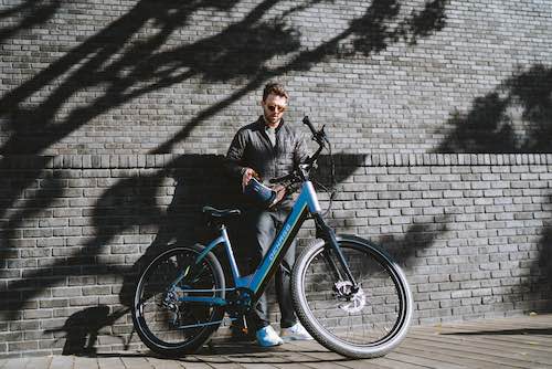 man leaning against a wall with Denago City Model 2 eBike